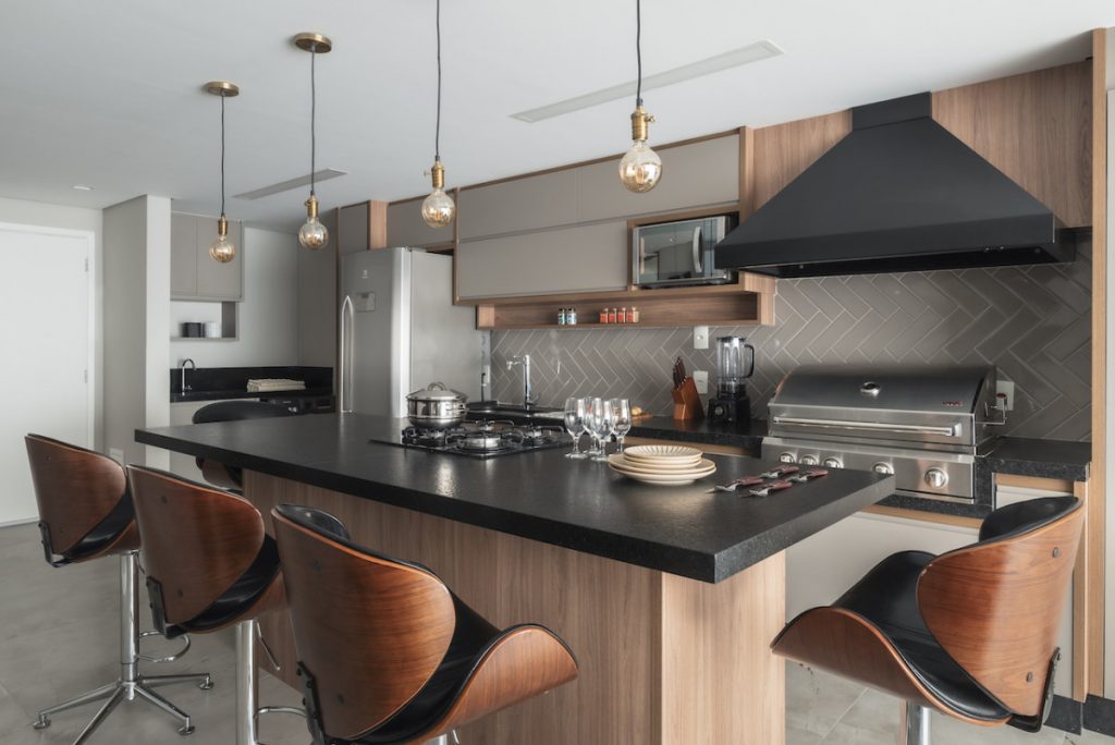 Cozinha ampla, com bancada granito preta, armário de cozinha marrom e duas cadeiras
