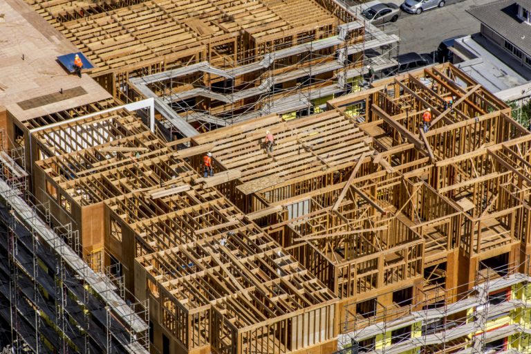 Empreendimento residencial em construção com madeiras segurando estrutura e homens trabalhando