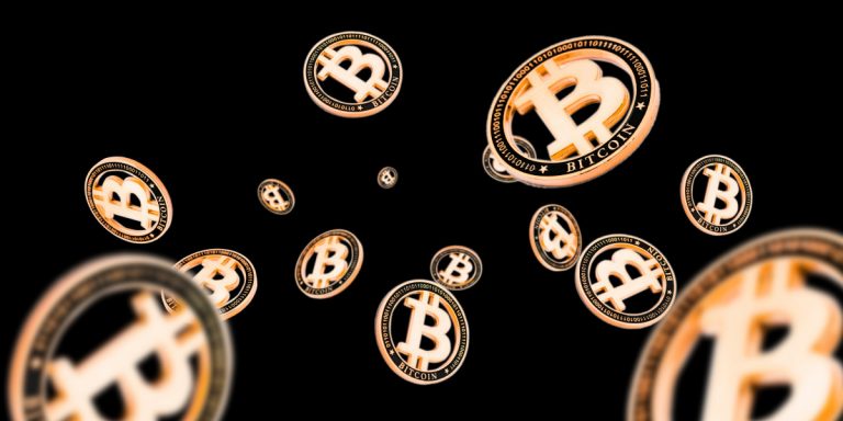 Na imagem vemos uma ilustração com dezenas de criptomoedas douradas de bitcoin